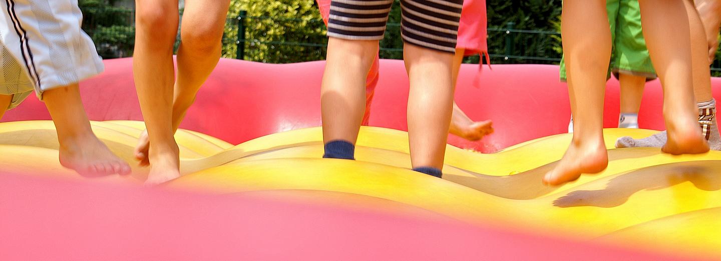 Kinderbeine von den Knien abwärts auf einer Hüpfburg fotografiert