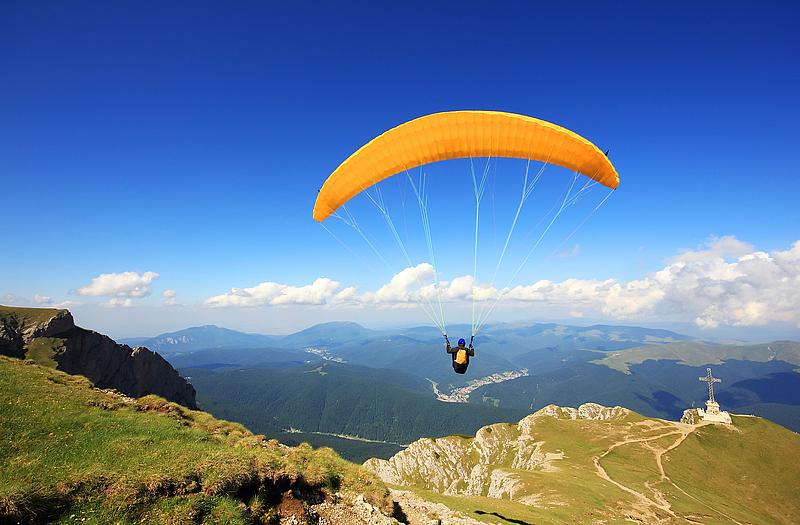 Ein Fallschirmspringer mit gelben Schirm gleitet in der Luft