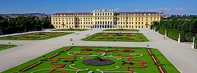 Ein gelbes Schloss, davor viele Blumen und ein grüner Rasen