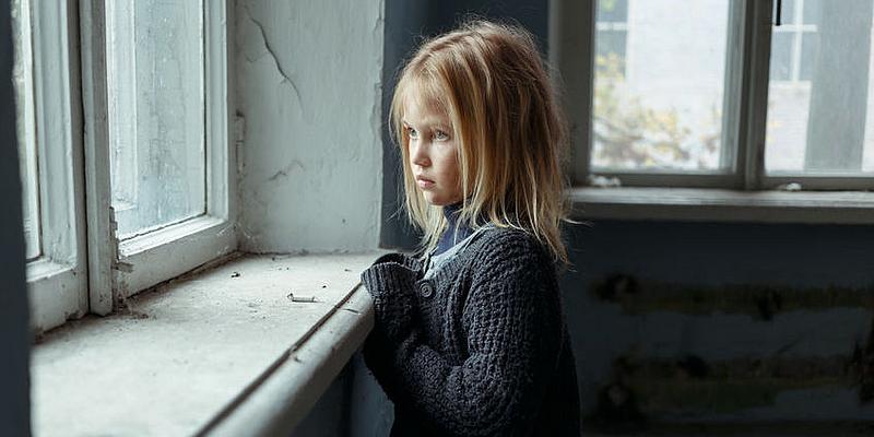 Armes Mädchen traurig aus dem Fenster blickend