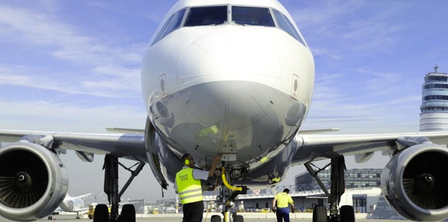 Detailansicht von einem Verkehrsflugzeug von Vorne mit 2 Arbeitern beim Flugzeug in Schutzweste