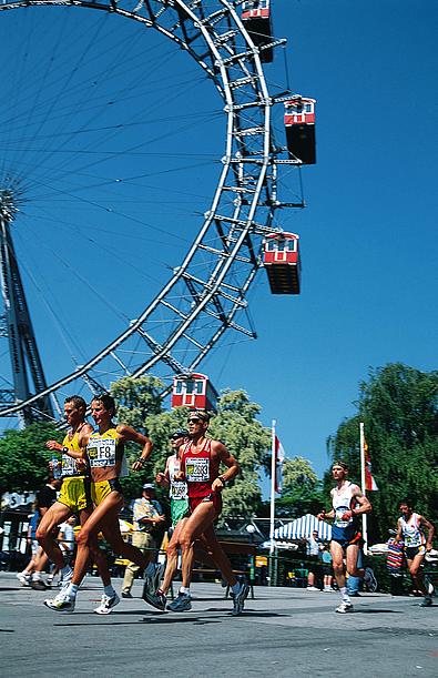 Die Sportlerinnen und Sportler laufen am Riesenrad vorbei.