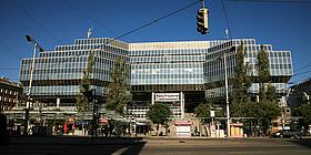 Vorderansicht des Bahnhofsgebäudes (Bank Austria-Gebäude). Am Bahnhofsvorplatz befinden sich Straßenbahnhaltestellen und Imbisbuden.