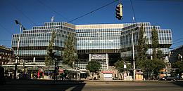 Vorderansicht des Bahnhofsgebäudes (Bank Austria-Gebäude). Am Bahnhofsvorplatz befinden sich Straßenbahnhaltestellen und Imbisbuden.