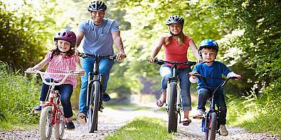 Familie ist auf einem Waldweg mit dem Rad unterwegs