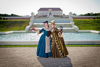 Zwei Frauen im Barockkostüm vor der Kleinen Kaskade auf der siebten Terrasse von Schlosshof