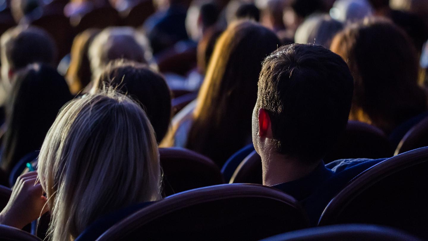 Menschen sitzen im Dunkeln und sehen sich einen Film an