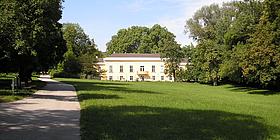 Eine große Wiese vor einem weißen Schloss bei Sonnenschein