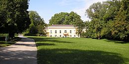 Eine große Wiese vor einem weißen Schloss bei Sonnenschein