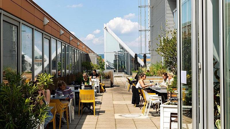 Menschen die auf einer Dachterrasse in einem Lokal sitzen