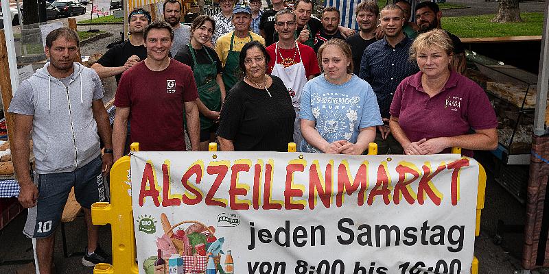 Menschen die Banner von Alszeilenmarkt in die Kamera halten