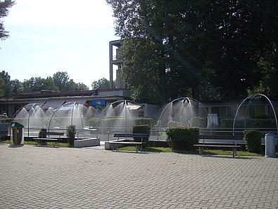 Eine größere betonierte Fläche, dahinter Wiese und Wiesensprenganlagen.