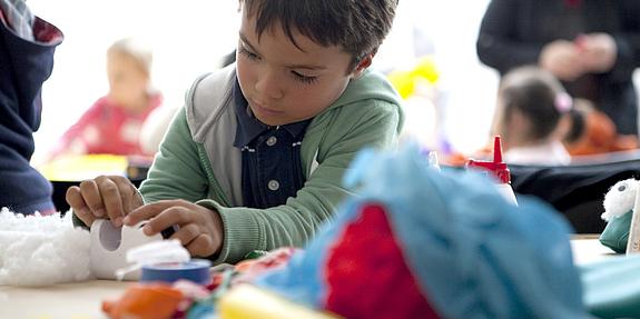 Ein Junge bastelt mit Wolle im Kinderatelier