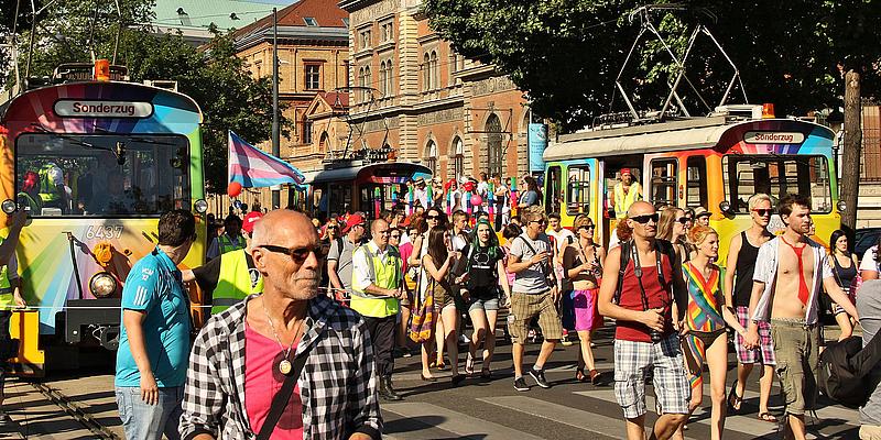 Regenbogenparade Bunte Straßenbahnen neben Menschenmassen auf der Regenbogenparade
