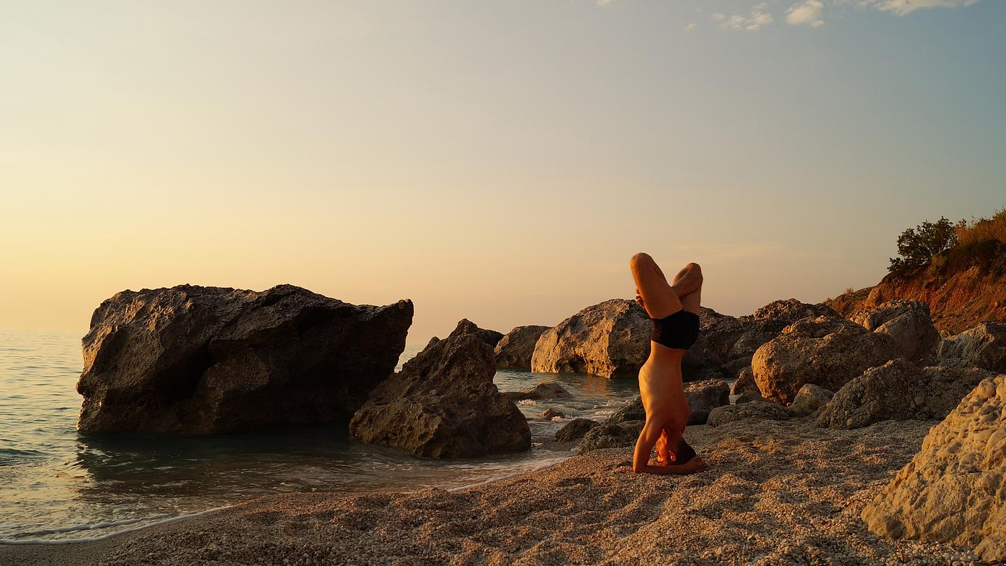 Eine Person macht Yoga am Strand. 