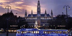 Der Rathausplatz in Wien in der vorweihnachtszeit mit violetter Straßenbahn im Vordergrund.