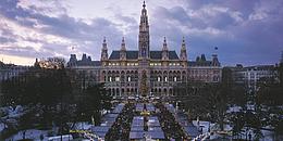 Bild von Weihnachtsmarkt vorm Wiener Rathaus bei Abenddämmerung.