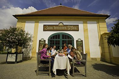 Gedeckter Tisch und Gäste vor dem Eingang zum Restaurant "Zum weissen Pfau" auf Schlosshof