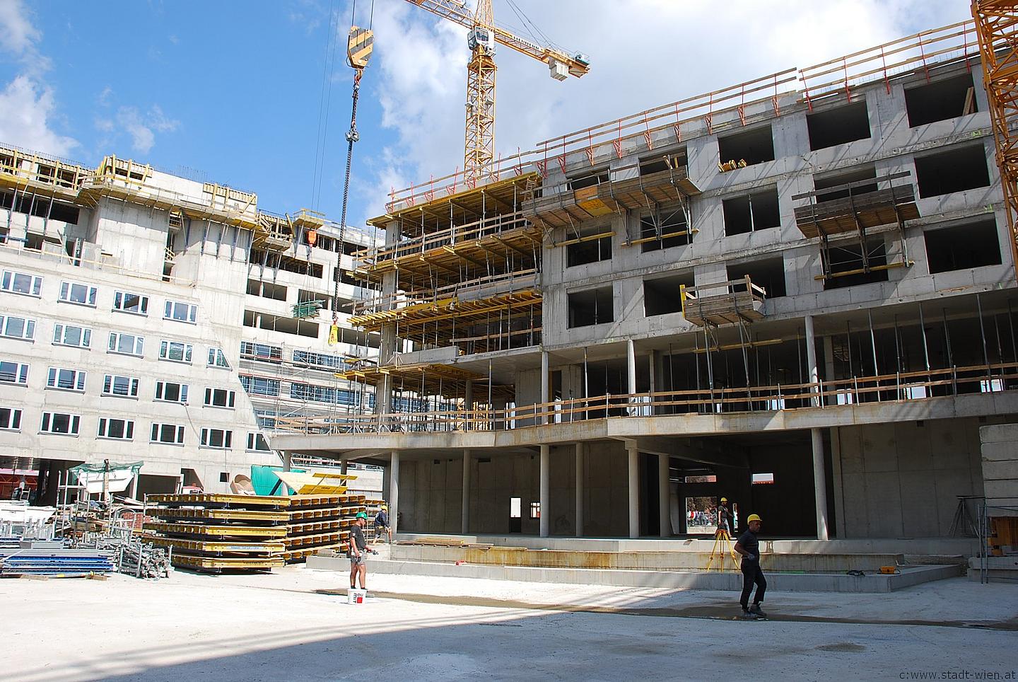 Das base 22 Studentewohnheim im Rohbau bei der Dachgleiche. Mehrstöckiges Gebäude. Davor liegt Baumaterial. Im Hintergrund ist ein hoher Kran zu sehen.