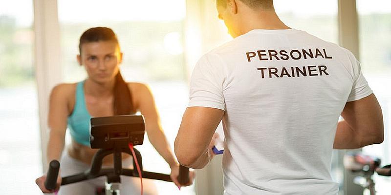 Mädchen sitzt auf Fahrrad, Personal Trainer leitet sie an.