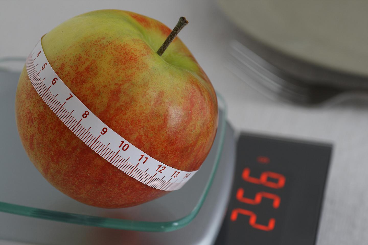 Apfel mit Maßband auf einer Waage 