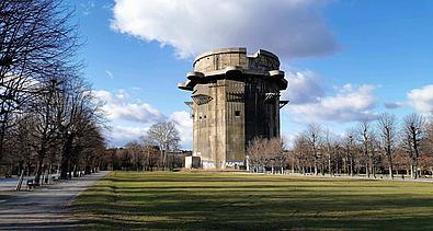 Ein riesiger Flakturm aus dem Zweiten Weltkrieg vor einer weiten grünen Wiese.