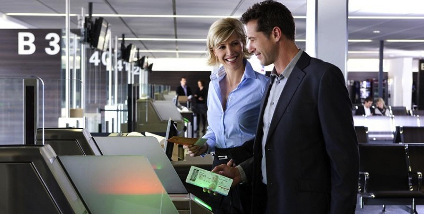 Mann und Frau stehen am Check-In Automaten am Flughafen Wien