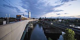 U-Bahn überquert in der Dämmerung eine Brücke über die Donau