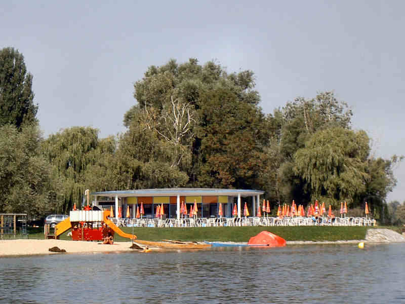 Ein Restaurant und ein kleiner Spielplatz am Strand vom Wasser aus gesehen