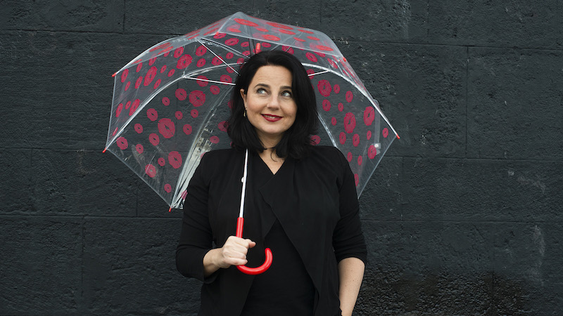 Nadja Maleh mit Regenschirm und verschmitztem Lächeln schaut nach oben