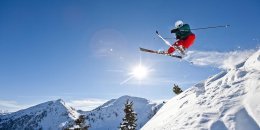 Skifahrer im Sprung, Schnee und Berge im Hintergrund