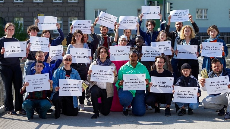 Black Voices Volksbegehren: Eine Gruppe Menschen, alle halten Banner mit Botschaften hoch