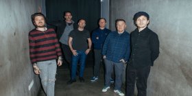 Die Bandmitglieder der Dropkick murphys stehen in einem schwach beleuchteten Gang