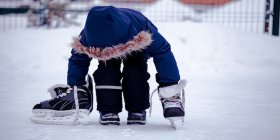 Kind auf dem Eis mit Eislaufschuhen.