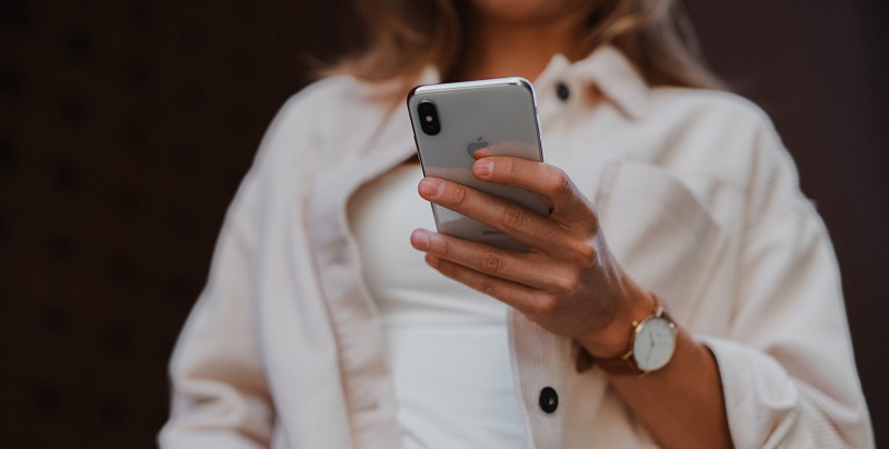 Das Bild zeigt eine Frau, die ein Smartphone hält. 