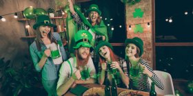 Fünf junge Menschen trinken und feieren den St Patrick's Day zusammen