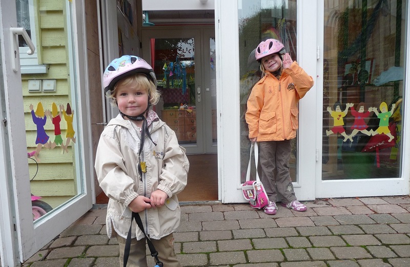 Das Bild zeigt zwei Kinder vor dem Eingang eines Kindergartens. 