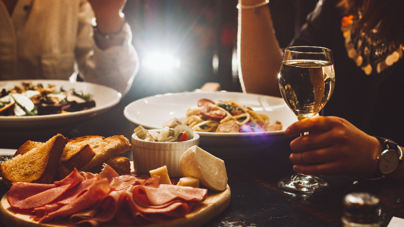 Menschen die in einer Bar warme Speisen konsumieren und dabei Alkohol trinken