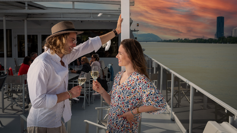 Zwei Menschen die an Board eines Schiffes bei Sonnenuntergang miteinander sprechen