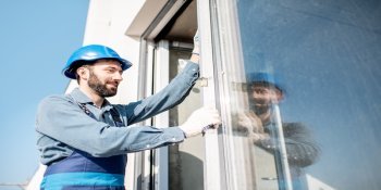 Mann auf Leiter baut neues Fenster ein