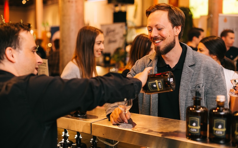 Barkeeper schenkt Gin an Messebesucher aus.