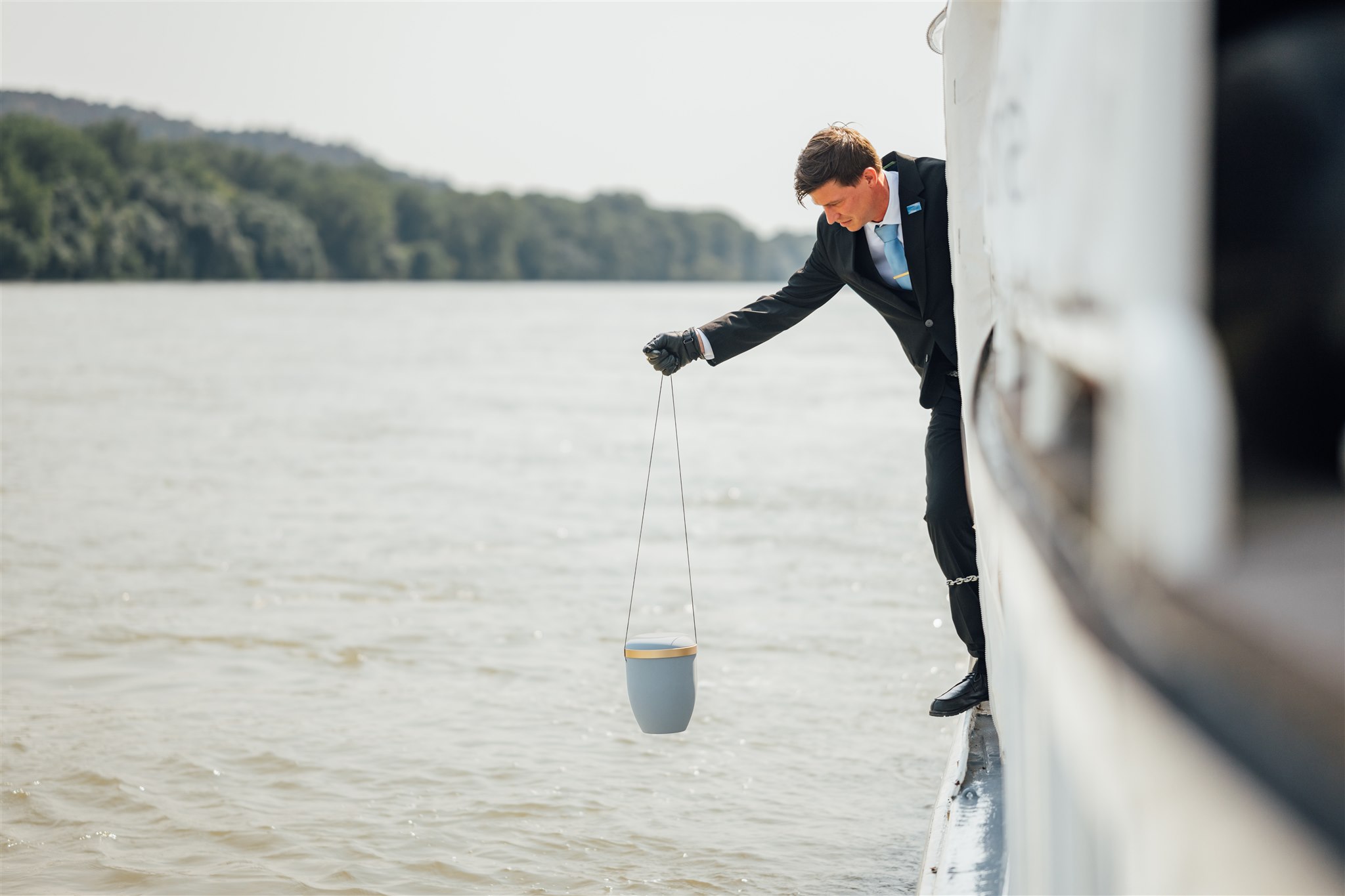 Mann lässt Urne zu Wasser in die Donau bei Bestattung