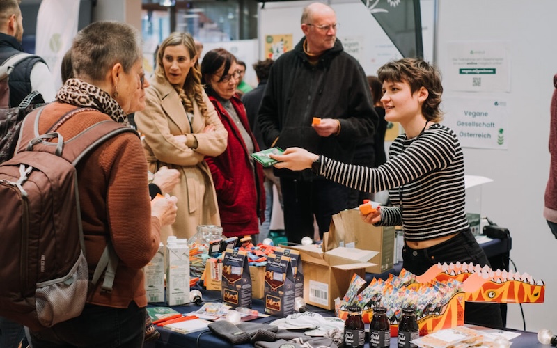 Besucher bei einem Messestand, Ausstellerin präsentiert Produkte