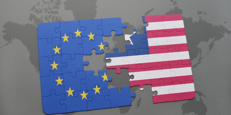 Die Flaggen der EU und der USA als Puzzle bei dem einige Teile fehlen. Im Hintergrund eine Weltkarte