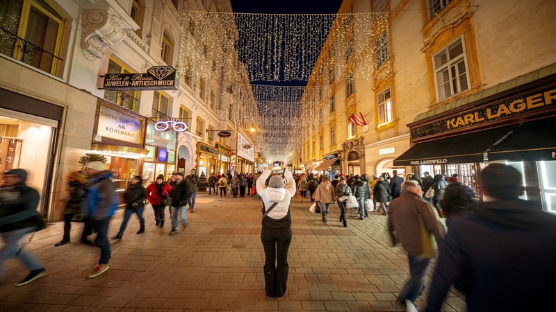 Frau fotografiert Weihnachtsbeleuchtung in der Wiener Innenstadt.