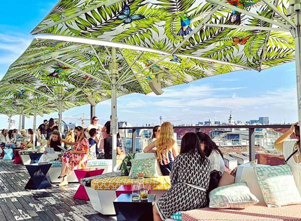 Menschen die zusammen auf der Dachterrasse einer Bar über den Dächern Wiens sitzen