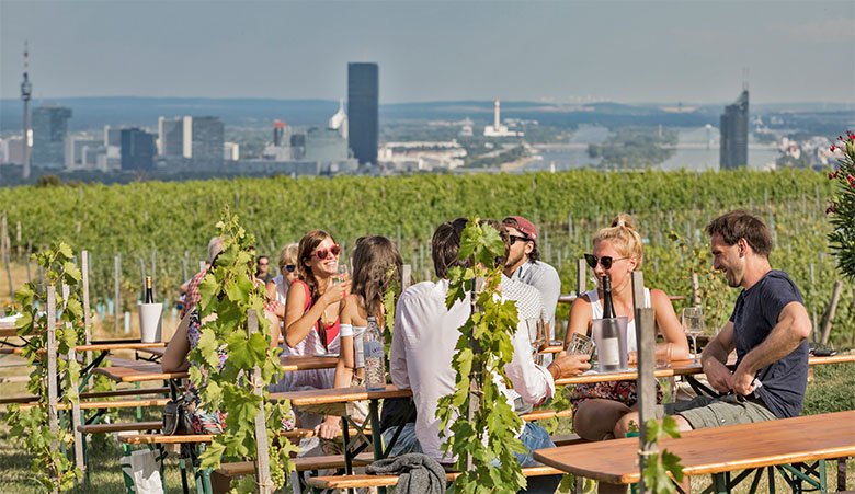 Menschen die in Wien beim Heurigen sitzen